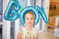 Young happy blonde girl with baloons smiling close up, lifestyle real people concept. Baloons shaped letters boy on the head of Royalty Free Stock Photo