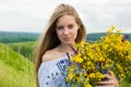 Young happy bride holding bouquet of blooming yellow flowers in countryside. Picture of beautiful happy girl with long light hair