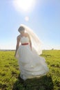 Young happy bride in long white dress walking on green field Royalty Free Stock Photo