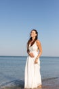 A young girl in a white sundress is walking along the seashore Royalty Free Stock Photo