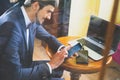 Young happy businesman working at cafe, using mobile phone