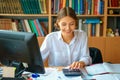 Young happy business lady in white shirt sitting at table with computer and papers working environment Royalty Free Stock Photo