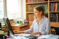 Young happy business lady in white shirt sitting at table with computer and papers working environment Royalty Free Stock Photo