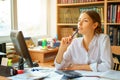 Young happy business lady in white shirt sitting at table with computer and papers working environment Royalty Free Stock Photo