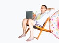 Young happy business man in beach shorts hold cocktail working with laptop on deckchair on white background Royalty Free Stock Photo