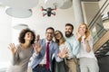 Young happy business people letting the drone camera to fly over the office and having fun