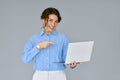 Young happy business woman pointing at laptop isolated on grey background. Royalty Free Stock Photo