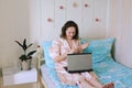 Young happy business woman lies in bed in pajamas in a cozy home. Online working, studying from home with laptop. Freelancer Royalty Free Stock Photo