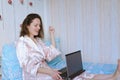 Young happy business woman lies in bed in pajamas in a cozy home. Online working, studying from home with laptop. Freelancer Royalty Free Stock Photo