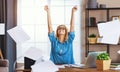 Young happy business woman working on computer and throws up papers in office