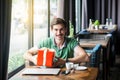 Young happy businessman in green t-shirt sitting and holding big red gift box and looking at camera with toothy smile. business Royalty Free Stock Photo