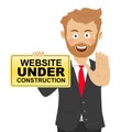 Young happy businessman holds a safety sign with website under construction text and showing stop gesture