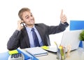 Young happy businessman smiling confident talking on mobile phone at office computer desk Royalty Free Stock Photo