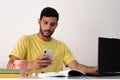 Young happy businessman smiling while reading his smartphone. concentrated student looking for information on his phone. Royalty Free Stock Photo