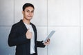 Young Happy Businessman Smiling and Show Thumbs Up while Using Digital Tablet. Standing by the Industrial Concrete Wall. Looking Royalty Free Stock Photo