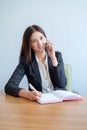 Young happy businesswoman talking on the phone and writing notes in office Royalty Free Stock Photo