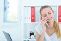 Young smiling businesswoman talking on the phone and writing notes in office. Royalty Free Stock Photo