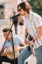 Young happy buskers drummer and guitarist playing music