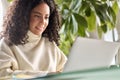 Young happy latin girl student using laptop looking at computer at home office. Royalty Free Stock Photo