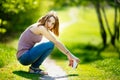 Young happy Caucasian blonde woman with coffee beverage sitting in park