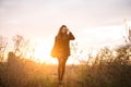 Young happy caucasian brunette woman walking through grassy meadow at sunset and smiling Royalty Free Stock Photo