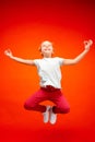 Young happy caucasian teen girl jumping in the air, isolated on red studio background. Royalty Free Stock Photo