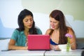 Young happy caucasian woman and beautiful hispanic girl working at office cafe with laptop computer discussing as digital business Royalty Free Stock Photo