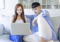 Young happy cheerful family couple resting on sofa in living room searching internet  on laptop Royalty Free Stock Photo