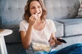 Young happy cheerful fuuny woman watchingTV, movies and eating popcorn, spending time at home Royalty Free Stock Photo