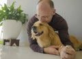 Young happy and cheerful man at home playing with his dog, a beautiful retriever, the guy smiling sweet cuddling the pet in Royalty Free Stock Photo