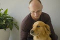 Young happy and cheerful man at home playing with his dog, a beautiful retriever, the guy smiling sweet cuddling the pet in Royalty Free Stock Photo