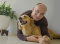 Young happy and cheerful man at home playing with his dog, a beautiful retriever, the guy smiling sweet cuddling the pet in Royalty Free Stock Photo