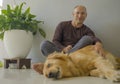 Young happy and cheerful man at home playing with his dog, a beautiful retriever, the guy smiling sweet cuddling the pet in Royalty Free Stock Photo