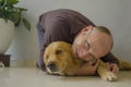 Young happy and cheerful man at home playing with his dog, a beautiful retriever, the guy smiling sweet cuddling the pet in Royalty Free Stock Photo