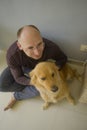 Young happy and cheerful man at home playing with his dog, a beautiful retriever, the guy smiling sweet cuddling the pet in Royalty Free Stock Photo