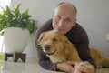 Young happy and cheerful man at home playing with his dog, a beautiful retriever, the guy smiling sweet cuddling the pet in Royalty Free Stock Photo