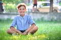 Young happy child boy relaxing on green grass in summer park. Positive kid enjoying summertime outdoors. Child wellbeing Royalty Free Stock Photo