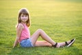 Young happy child girl resting while sitting on green grass lawn on warm summer day Royalty Free Stock Photo