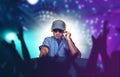 Young happy and cool DJ playing music at party event in night club mixing techno songs on laser and flash lights background Royalty Free Stock Photo