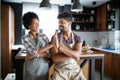 Young happy couple in aprons giving high five in kitchen Royalty Free Stock Photo