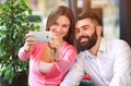 Young happy couple in cafe having fun, chatting and taking selfies together Royalty Free Stock Photo