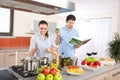Young happy couple cook in kitchen with cookbook Royalty Free Stock Photo