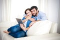 Young happy couple on couch at home enjoying using digital tablet computer Royalty Free Stock Photo