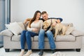 Young happy couple with dog sitting on sofa Royalty Free Stock Photo