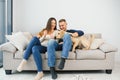 Young happy couple with dog sitting on sofa Royalty Free Stock Photo