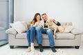 Young happy couple with dog sitting on sofa Royalty Free Stock Photo