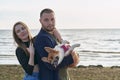 Young happy couple with dog standing on beach. Beautiful girl and guy and Corgi puppy having fun Royalty Free Stock Photo