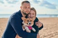 Young happy couple with dog standing on beach. Beautiful girl and guy and Corgi puppy having fun Royalty Free Stock Photo