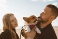 Young happy couple with dog taking selfie photo on beach. Beautiful family and Corgi puppy Royalty Free Stock Photo