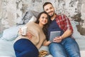 Young happy couple drinking coffee or tea in bed at the morning. Reading news, using tablet Royalty Free Stock Photo